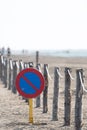 Vertical image of a no parking traffic sign on a beach with a wooden log fence attached with a rope Royalty Free Stock Photo