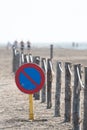 Vertical image of a no parking traffic sign on a beach with a wooden log fence attached with a rope Royalty Free Stock Photo