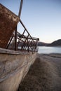 Vertical image of an old rusty wrecked boat at the edge of a lake