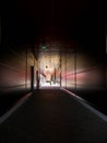 Vertical image, people passing through the dark corridor at local mall.