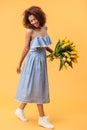 Vertical image of pleased african woman holding bouquet flowers