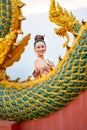 Vertical image portrait of beautiful Asian woman with Thai traditional dress stand behide the naga sculpture in temple area also