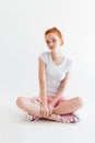 Vertical image of pretty ginger girl sitting on the floor