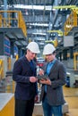 Vertical image of professional manager or engineer workers discuss together with tablet in front of electrical or metro train in