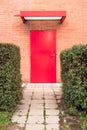 Vertical image. Red door surrounded by orange brick wall.