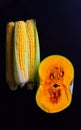 Vertical image of ripe half pumpkin and corn on black background. Thanksgiving day concept Royalty Free Stock Photo