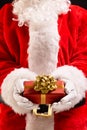 Vertical image of santa claus holding christmas present with copy space on black background Royalty Free Stock Photo