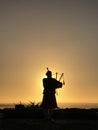Vertical image of the silhouette of a bagpiper at sunset in Carmel, California in front of the Pacific Ocean Royalty Free Stock Photo
