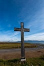 Vertical image, simple oak wood catholic cross near curving asphalt road