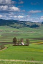 Vertical image, small catholic church on hilltop surrounded by green agricultural field