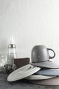 Vertical image.Stack of clean fresh dishes,cup, sponge, scraper, glass bottles of natural detergent on the grey table against whit