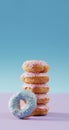 Vertical image of stack of donuts with pink and blue frosting on pink and blue background