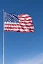 Vertical image of the stars and stripes of the American flag against a deep blue sky. Royalty Free Stock Photo