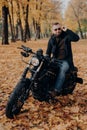 Vertical image of thoughful biker wears sunglasses, rides motorbike in park, poses on street, wears stylish clothing, enjoys spare