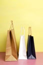 Vertical image.Three shoppin bags on the pink desk against bright yellow wall Royalty Free Stock Photo