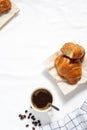 Vertical image,Top view of c  roissant and hot coffee cup placed on bedsheet with soft light in the morning. Royalty Free Stock Photo