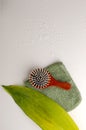 Vertical image.Top view of green tropical leaf, towel and wooden hair brush on the wet beige surface