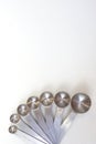 Vertical image of top view kitchenware steel measuring spoons on white background. Materials or kitchen equipment for bakery. Royalty Free Stock Photo