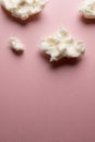 Vertical image of tufts of homemade white candy floss, on pink background with copy space