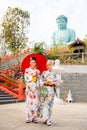 Vertical image of two Asian women wear japanese style dress with one hold red umbrella and stand in front of stair to green big Royalty Free Stock Photo