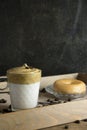 Vertical image of whipped instant coffee on top of a glass of milk with a doughnut on a wooden tray with coffee beans sprinkled.