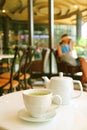 Vertical image of a white cup and teapot of green tea served on cafe`s white table Royalty Free Stock Photo