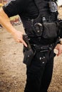 Vertical image of white male caucasian police officer reaching down and places hand on his weapon hand gun and pulls gun out of Royalty Free Stock Photo