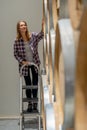 Vertical image of winery worker woman stand on the stairs to check the product in modern factory