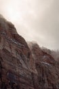 A vertical image of winter storm clouds drifting over the snow laced towering red sandstone cliffs of Zion national park Royalty Free Stock Photo