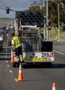 Vertical image of Worker behind utility truck placing bright orange traffic cones on roadway