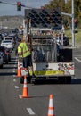 Vertical Image of Worker behind utility truck placing bright orange traffic cones on roadway