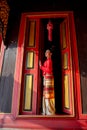 Vertical image of young Asian woman with Thai Lanna traditional dress stand at door with red color and old style of ancient house Royalty Free Stock Photo