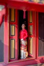 Vertical image of young Asian woman with Thai Lanna traditional dress stand at door with red color and old style of ancient house Royalty Free Stock Photo