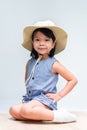 Vertical imaged of cute girl aged 4-5 years sitting in a folded pose, a child wearing a cream colored hat for adventure