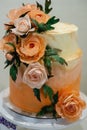 Vertical images of beautiful modern wedding cake decorated with pink flowers.