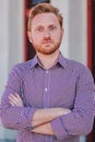 Vertical individual portrait of arms crossed serious young adult man standing outdoors and looking pensive at camera Royalty Free Stock Photo