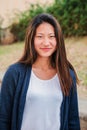 Vertical individual portrait of chinese young woman smiling and looking at camera ourside. Front view of asian teenage