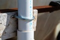 Vertical installation of a PVC pipe in an agricultural setting showing a clamp fastener