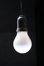 Vertical isolated shot of a hanging white lightbulb on a black background Royalty Free Stock Photo