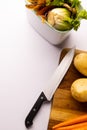 Vertical of knife and vegetables on chopping board with vegetable waste in kitchen composting bin Royalty Free Stock Photo