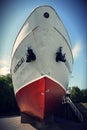 Vertical of a large white boat with two black anchors on the stern on a sunny day