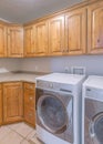 Vertical Laundry room interio with floor and wall wooden cabinets