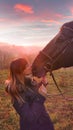 CLOSE UP: Cheerful young woman kisses her horse on the muzzle at golden sunset.