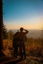 Vertical of a loving couple on top of a hill enjoying the view over mountains and the sunset sky Royalty Free Stock Photo