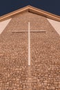 Vertical low-angle closeup of a stone wall of a church with a huge cross on it Royalty Free Stock Photo