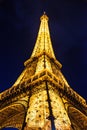 Vertical low-angle of the Eiffel tower during the evening with illuminated lights, in Paris France Royalty Free Stock Photo