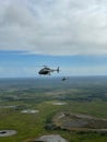Vertical low-angle of a helicopter flying in the air, green fields, cloudy sky background Royalty Free Stock Photo