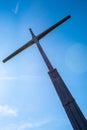 Vertical low angle shot of a big wooden cross against a blue sky. Royalty Free Stock Photo