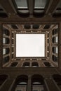 Vertical low angle shot of a building creating a suqare with white sky seen through it