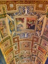 Vertical low angle shot of the ceiling of Vatican museum with colorful paintings